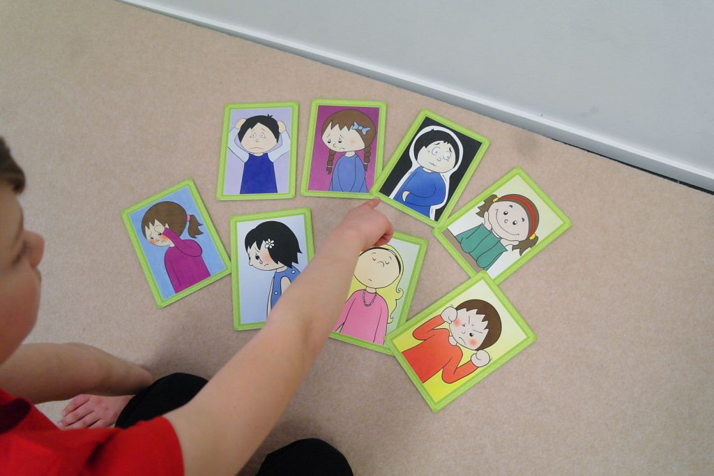 Terapianurkan ryhmäterapian palvelut, kuvassa lapsi osoittamassa kuvakortteja jotka esittävät eri tunteita