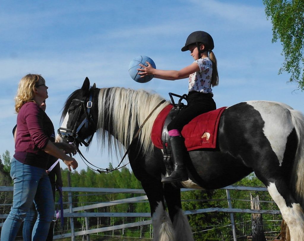 Terapianurkan ratsastusterapian palvelut lapsille, kuvassa lapsi hevosen selässä pallo kädessä